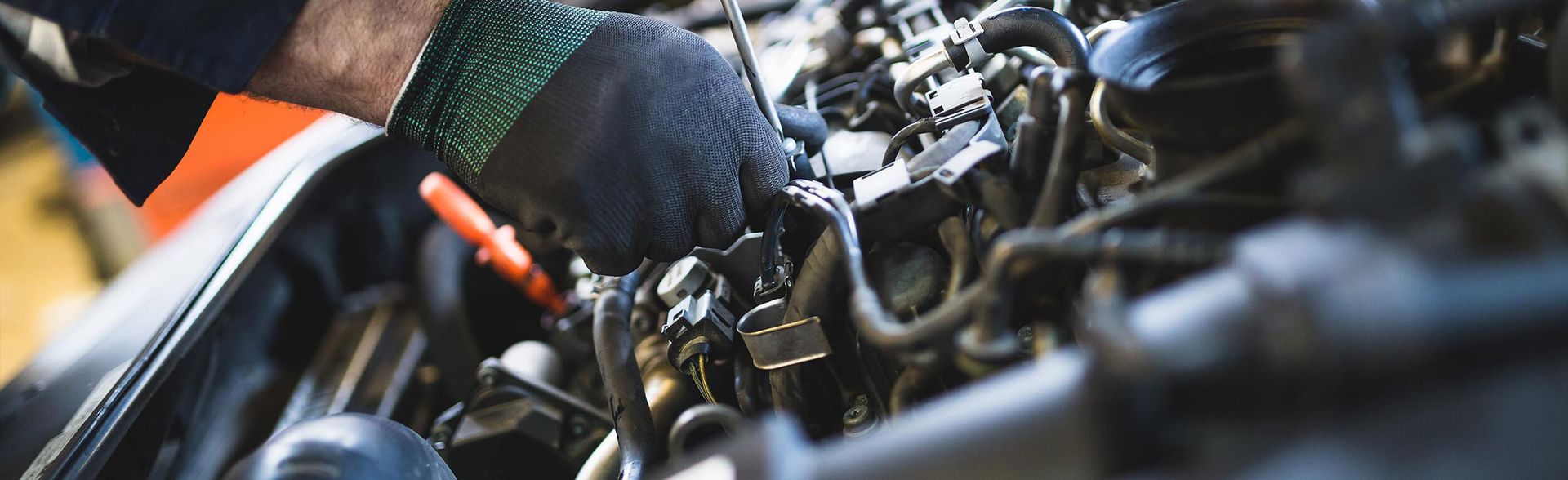 Die Hand eines Mechanikers bei der Arbeit an Motorteilen eines Autos.